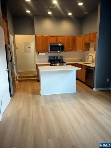 a large kitchen with stainless steel appliances granite countertop a stove a sink and a refrigerator