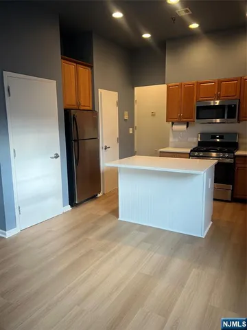 a large kitchen with stainless steel appliances a refrigerator and a stove top oven