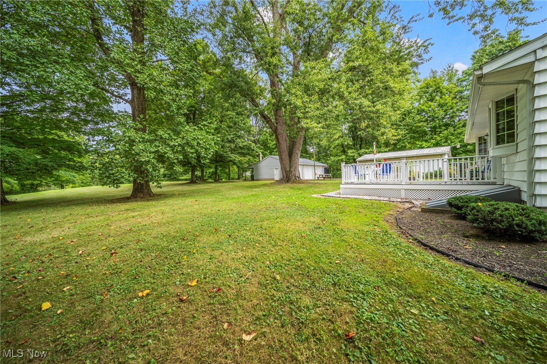2921 Sexton Road Geneva, OH 44041 - Photo 9 of 43 View of green lawn with a deck, view of scattered trees, and an outbuilding