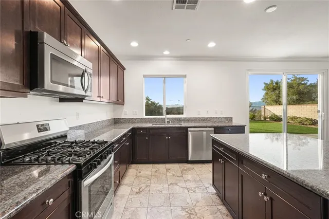 a kitchen with stainless steel appliances granite countertop a refrigerator a sink a stove and a refrigerator with wooden floor