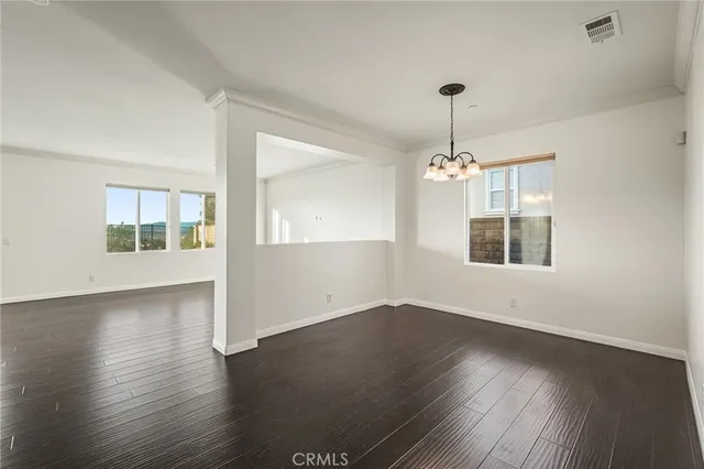 a view of a livingroom with wooden floor and a kitchen space with a sink