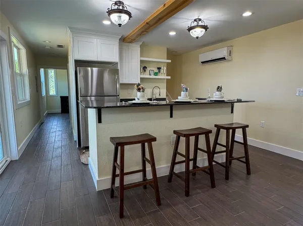 a kitchen with stainless steel appliances a dining table chairs refrigerator and sink