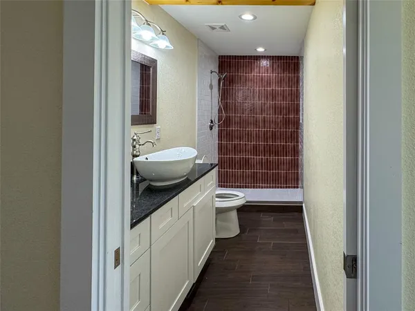 a bathroom with a granite countertop sink a toilet a mirror and shower