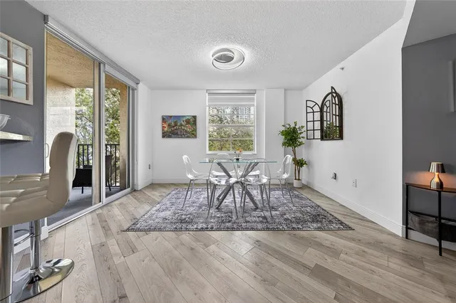 a dining room with wooden floor and a floor to ceiling window