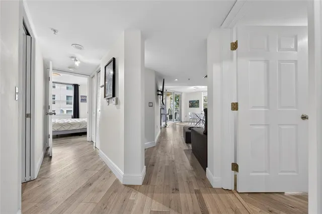 a view of a hallway with wooden floor closet and a bathroom