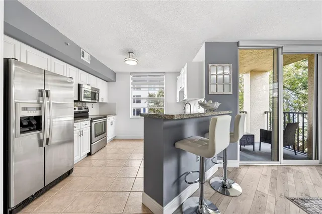 a kitchen with stainless steel appliances granite countertop a refrigerator a stove a sink dishwasher and white cabinets with wooden floor