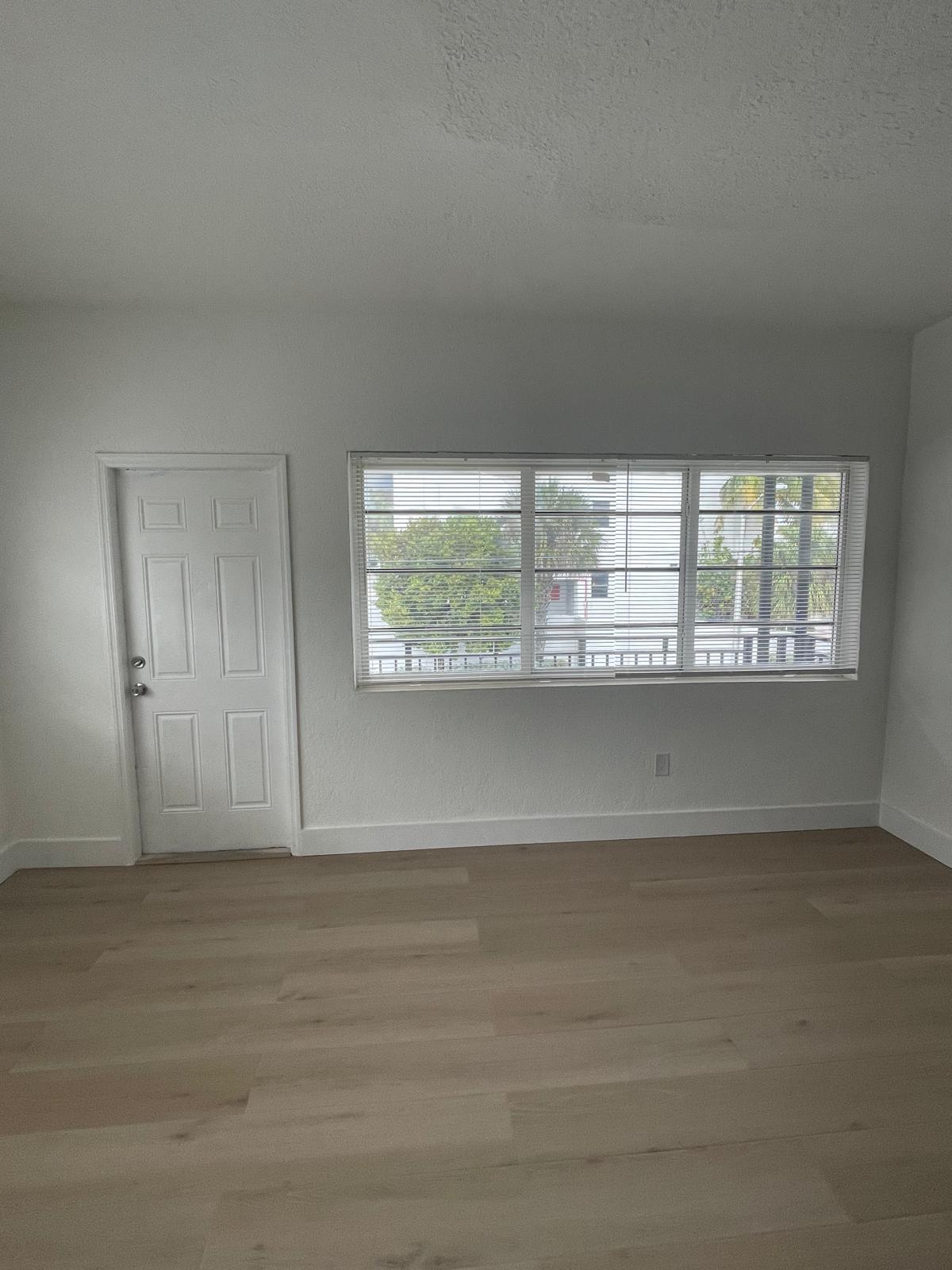 6910 Byron Avenue, Unit 3 Miami Beach, FL 33141 - Photo 1 of 12 an empty room with wooden floor and windows