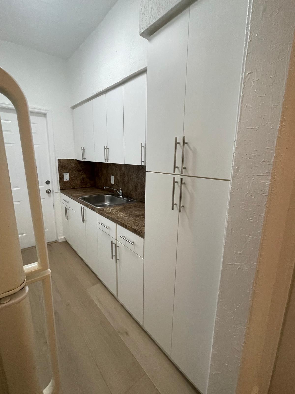 6910 Byron Avenue, Unit 3 Miami Beach, FL 33141 - Photo 3 of 12 a kitchen with white cabinets and white appliances