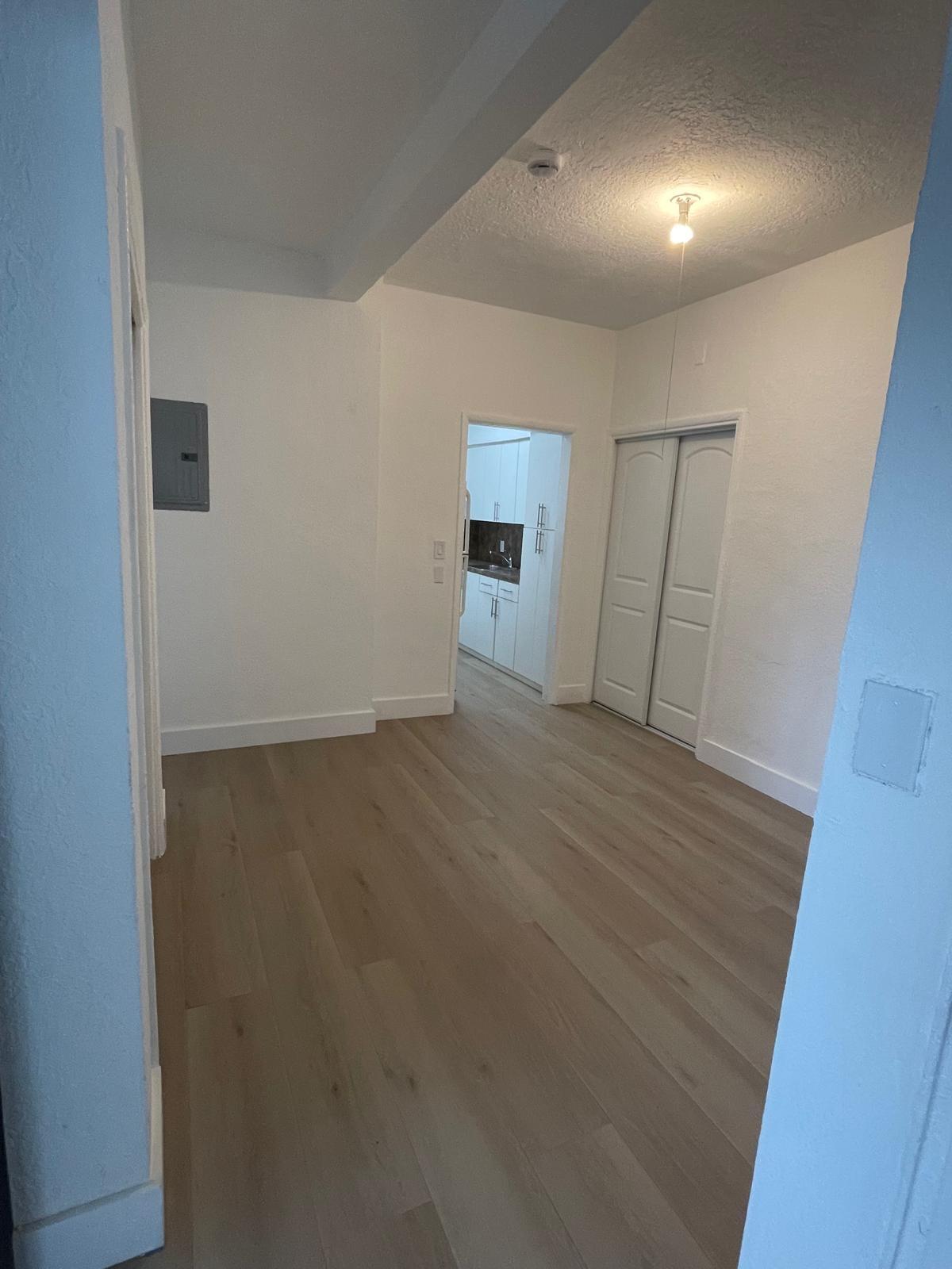 6910 Byron Avenue, Unit 3 Miami Beach, FL 33141 - Photo 7 of 12 an empty room with wooden floor and windows