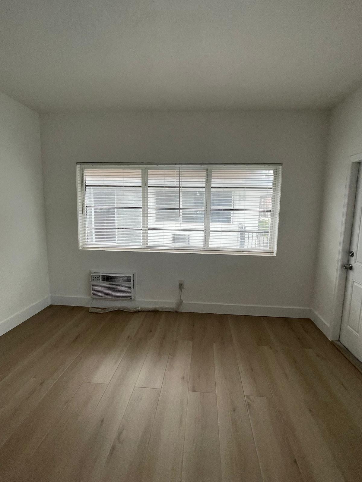 6910 Byron Avenue, Unit 3 Miami Beach, FL 33141 - Photo 9 of 12 an empty room with wooden floor and windows