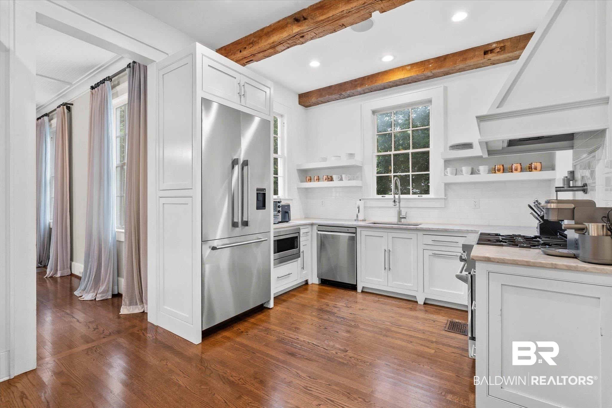 3863 Old Shell Road Mobile, AL 36608 - Photo 11 of 48 Gourmet kitchen with wood-finish flooring, white cabinetry, stainless steel appliances, exposed ceiling beams, and a built-in range hood