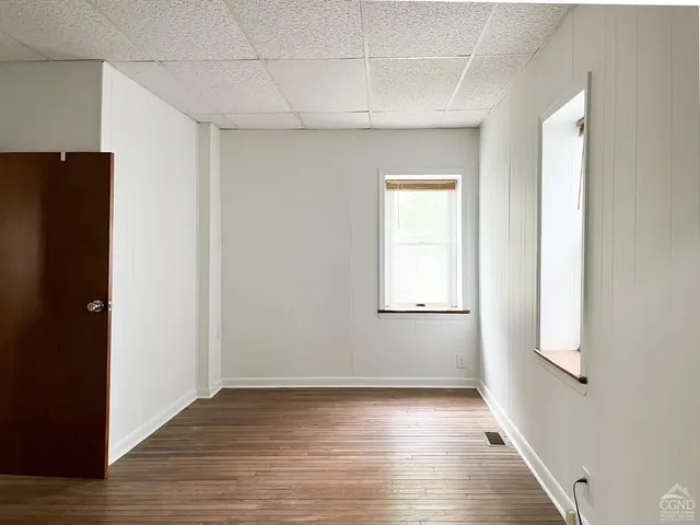 a view of an empty room with closet and wooden floor