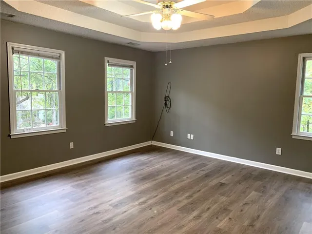 an empty room with wooden floor and windows