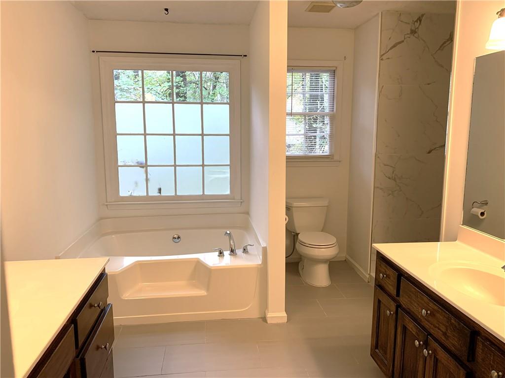 4235 Doubletree Court Cumming, GA 30040 - Photo 14 of 24 a bathroom with a granite countertop toilet a sink and a bathtub