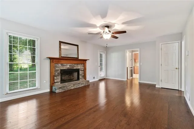 a view of an empty room with wooden floor fireplace and a window