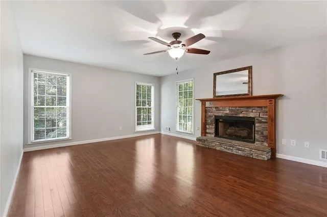 a view of an empty room with wooden floor fireplace and a window