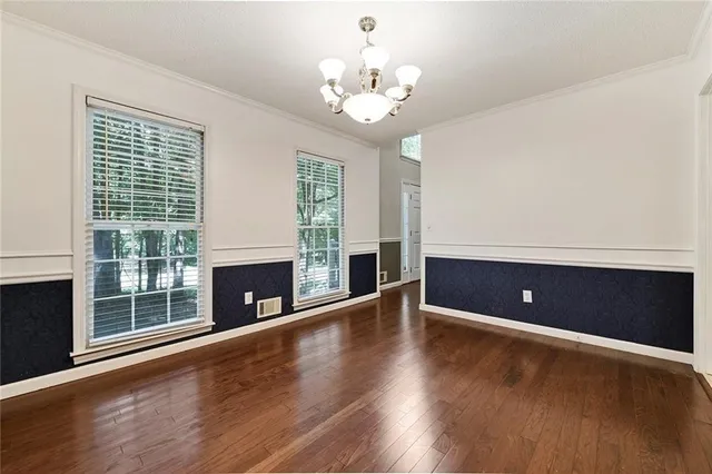 a view of an empty room with wooden floor and a fireplace