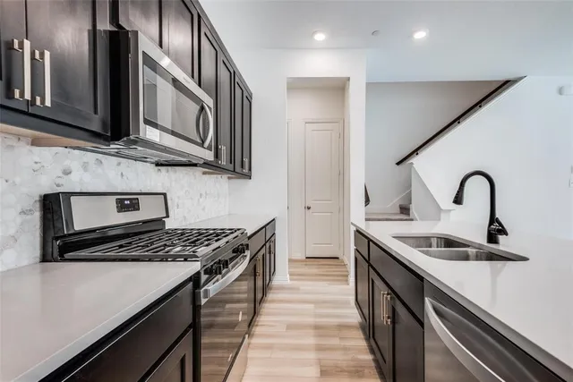 a kitchen with stainless steel appliances a sink a stove cabinets and a kitchen island