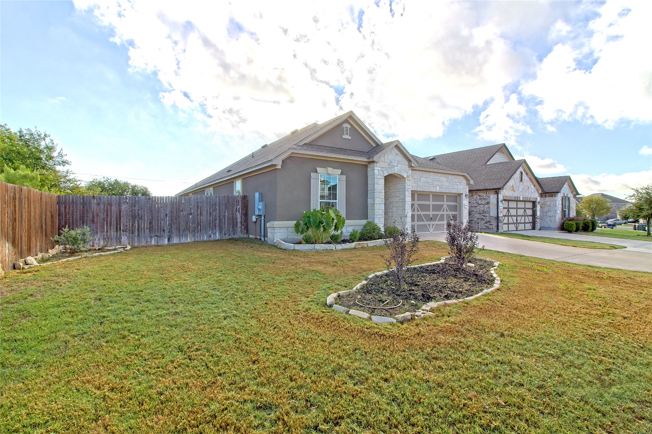 31443 Kingsway Road Georgetown, TX 78628 - Photo 2 of 40 Well-maintained front lawn with mature landscaping leads to a welcoming home featuring stone accents and an attached garage.