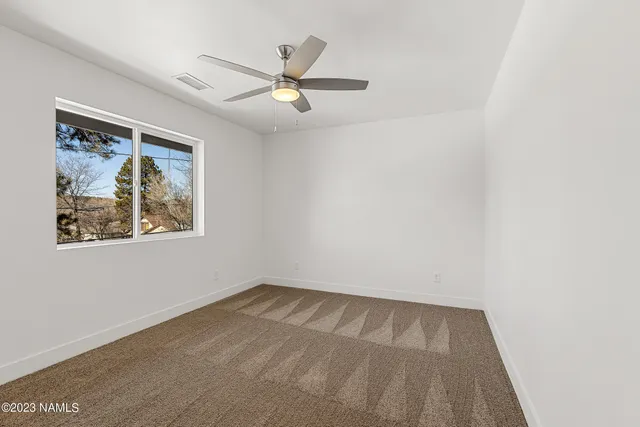 an empty room with a window and a fan