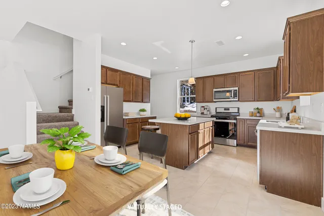 a kitchen with a sink stainless steel appliances and chairs