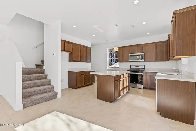a kitchen with granite countertop a sink a counter top space stainless steel appliances and cabinets