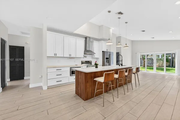 a large white kitchen with granite countertop a large window