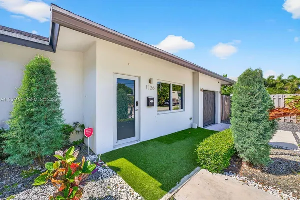 a front view of a house with a yard and potted plants