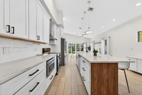 a open kitchen with kitchen island granite countertop a sink a counter space and stainless steel appliances