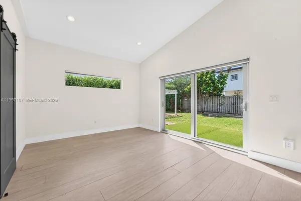 a view of an empty room with wooden floor and a large window