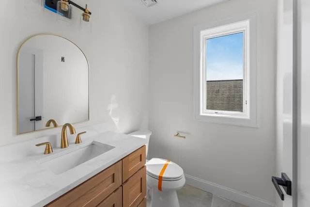 a bathroom with a granite countertop sink mirror vanity and toilet