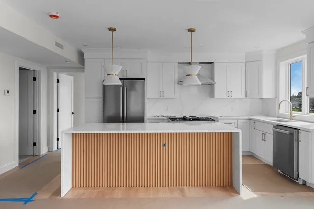 a kitchen with stainless steel appliances granite countertop a sink a stove a refrigerator and island