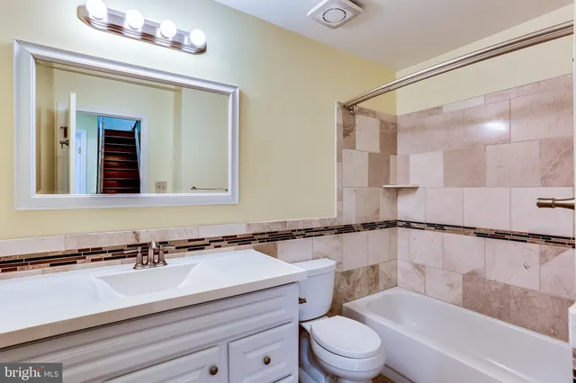 a bathroom with a sink a toilet a mirror and bathtub