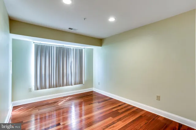 an empty room with wooden floor and closet area
