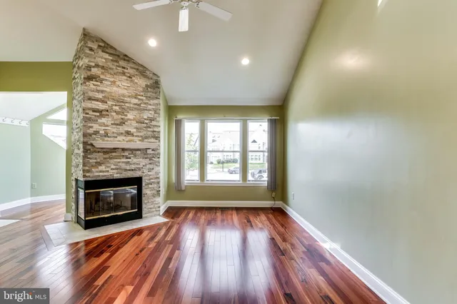 a view of an empty room with wooden floor fireplace and a window