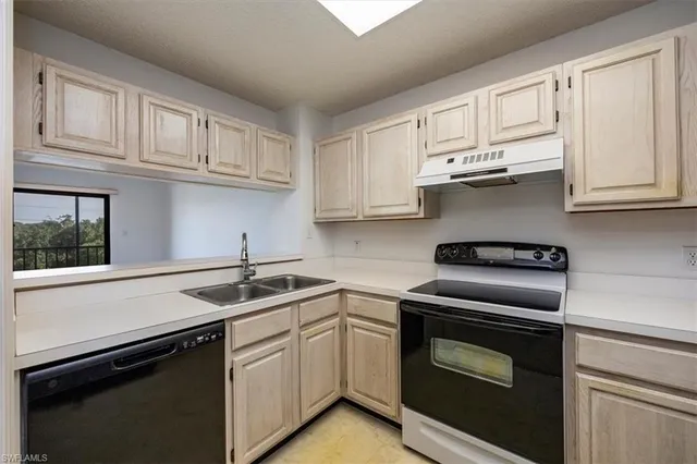 a kitchen with stainless steel appliances granite countertop white cabinets and a stove a sink