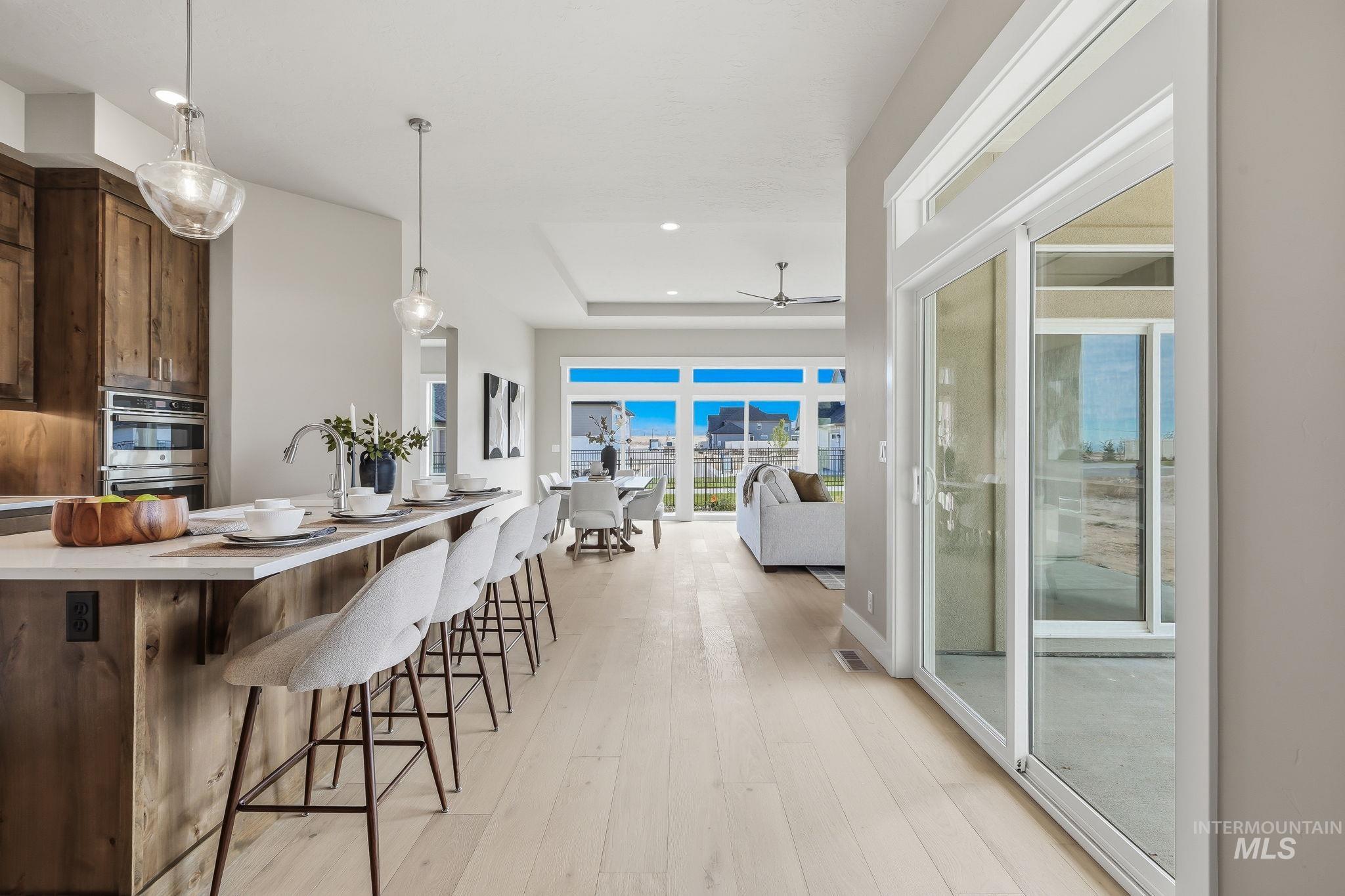 470 South Radiator Way Boise, ID 83716 - Photo 23 of 50 Open-concept living area featuring light wood-finish flooring, a kitchen island with seating, built-in stainless steel appliances, and abundant natural light from large windows and a sliding glass door