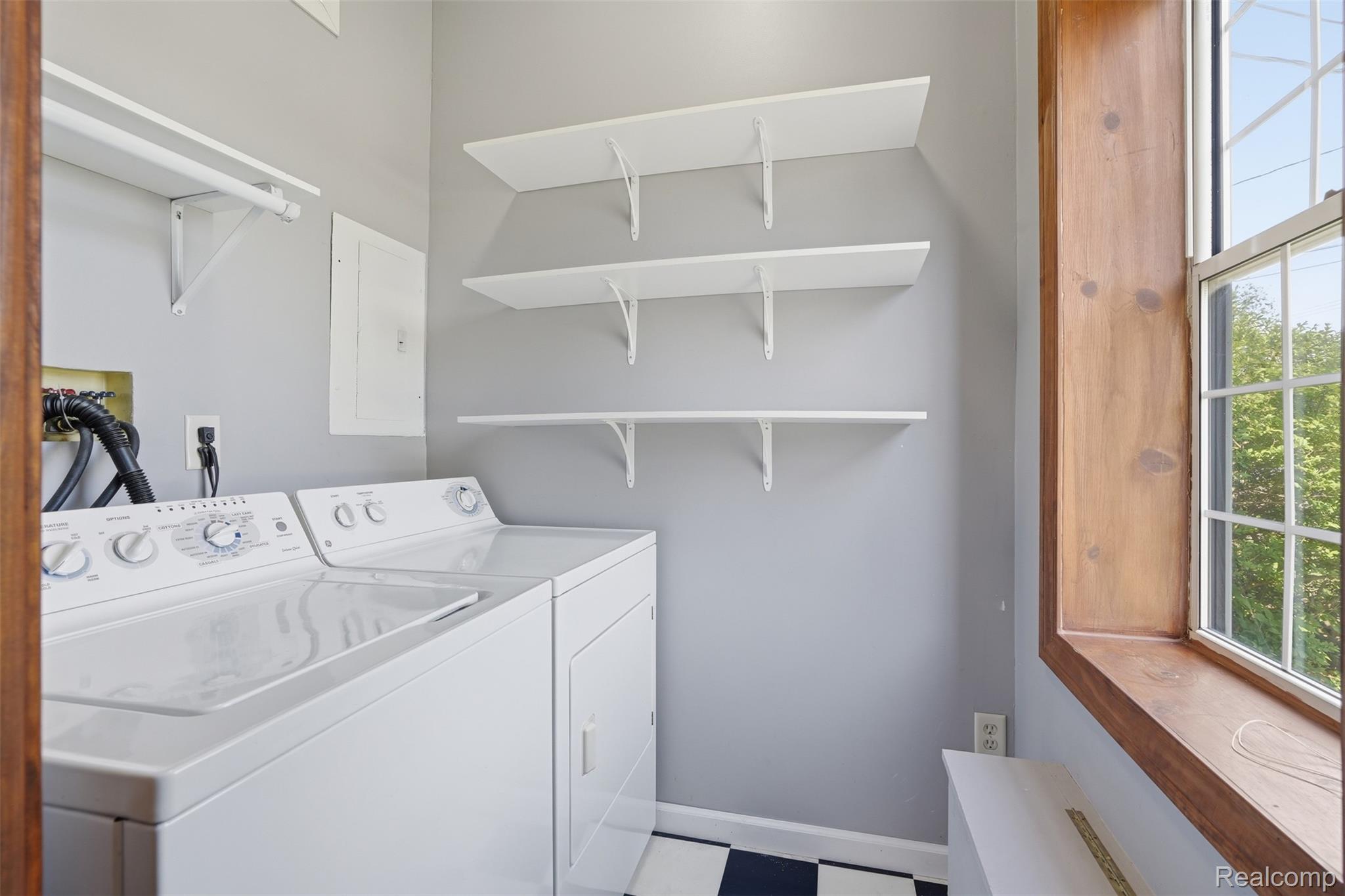 5634 Chicago Road Warren, MI 48092 - Photo 13 of 36 Laundry area with a checkered tile floor, multiple wall-mounted shelving units, and a wood-framed window