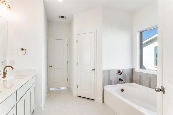 a bathroom with a tub a sink and mirror