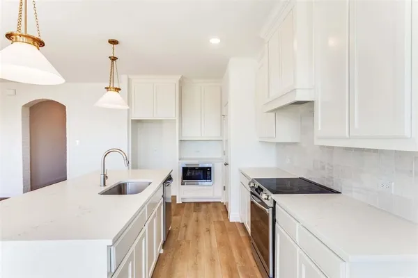 a kitchen with granite countertop a sink a stove and cabinets