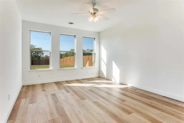 a view of empty room with wooden floor and fan
