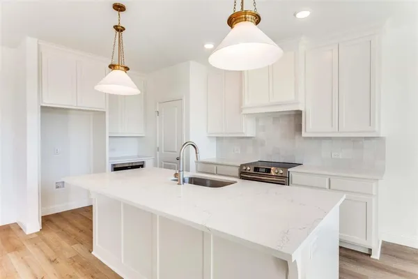 a kitchen with stainless steel appliances a sink a stove a chimney a refrigerator and cabinets