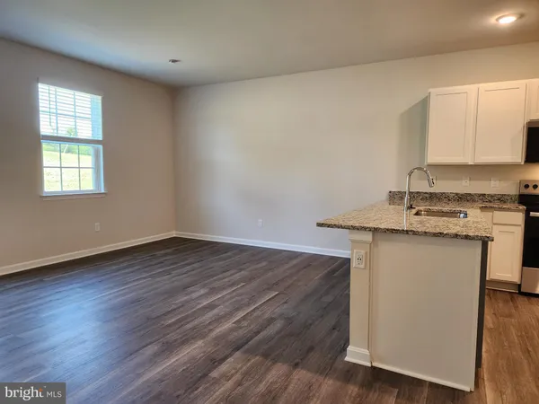 a kitchen with granite countertop wooden floors and white walls