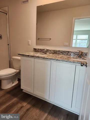 a bathroom with a granite countertop sink and a toilet