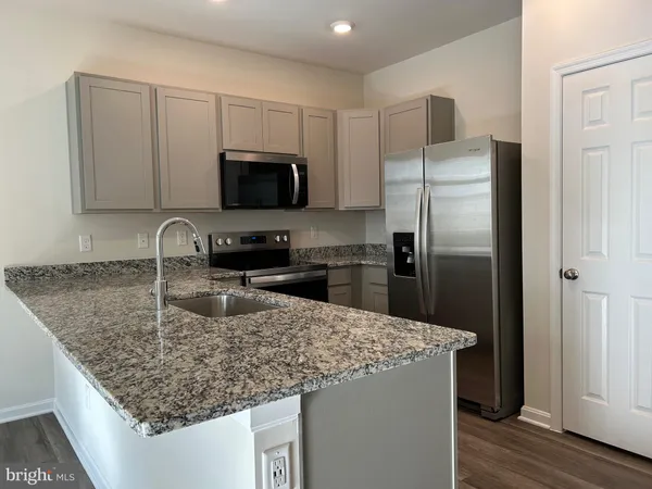 a kitchen with stainless steel appliances granite countertop a refrigerator a sink a stove a microwave and wooden cabinets