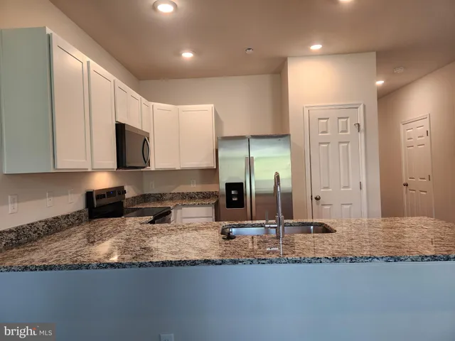 a view of a kitchen with granite countertop a sink and cabinets