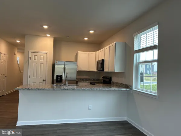 a view of a kitchen with stainless steel appliances granite countertop a stove a sink and a window