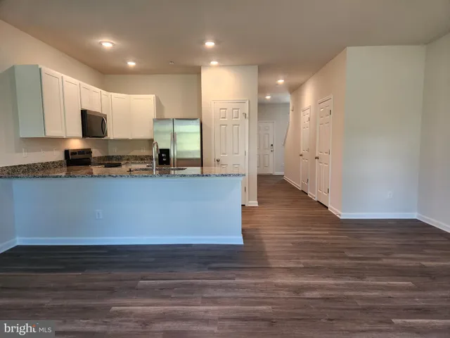 a view of kitchen with stainless steel appliances granite countertop cabinets and wooden floor