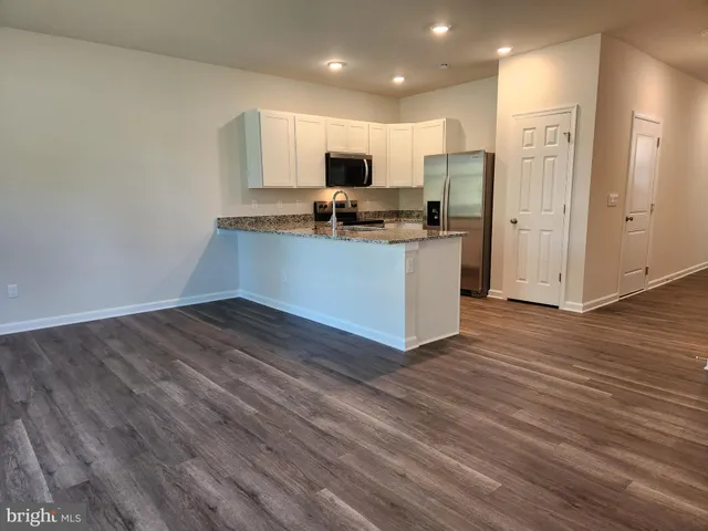 a kitchen with granite countertop a refrigerator and a stove top oven