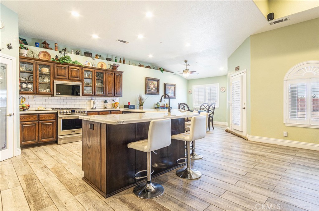 9735 Elsinore Road Oak Hills, CA 92344 - Photo 16 of 64 a kitchen with stainless steel appliances kitchen island granite countertop a sink and cabinets